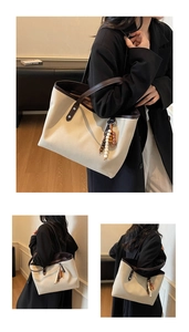 Macro shot showing contrasting brown leather trim and ethnic style wood bead charm on tote bag