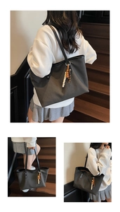 Detail of dark grey canvas tote bag featuring black leather trim and wood bead tassel