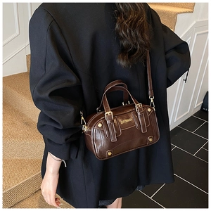 Deep brown Boston bag detail showing smooth PU leather texture and shoulder strap fit