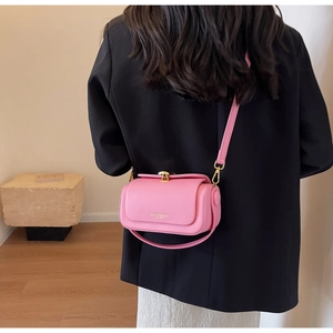 Detail of pink leather crossbody bag with logo worn over a black blazer for chic style