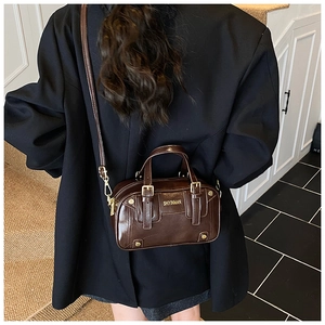 Detail of dark brown glossy leather crossbody bag with gold logo and hardware