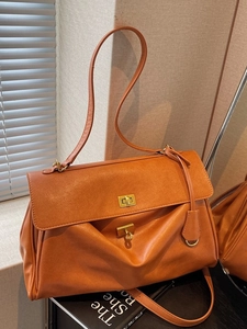 Orange-brown retro leather tote bag with gold swivel lock and dual straps on table