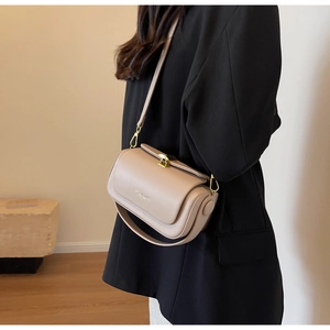 Detail of minimalist beige crossbody bag featuring gold hardware and dual strap options