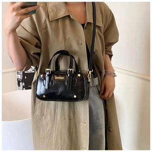 Detail of black faux leather crossbody bag with gold logo and adjustable shoulder strap