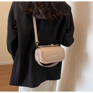 Detail of beige leather crossbody bag with golden clasp and adjustable shoulder strap