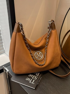 Brown suede shoulder bag with M logo and metal chain strap in minimalist retro style