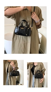 Close-up of glossy black pillow bag featuring gold metal hardware and adjustable strap