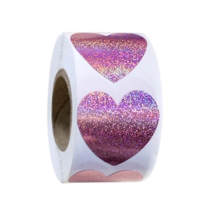 Close-up of holographic heart stickers roll with pink purple gradient for gift sealing