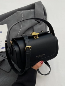 Structured black leather cylinder bag with gold shell clasp and adjustable shoulder strap