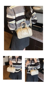 Lifestyle view of a cream white glossy faux leather satchel with gold brand logo