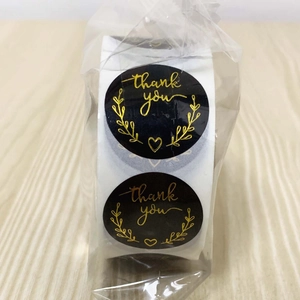 Close-up of black and gold foil Thank You stickers on a roll for business packaging
