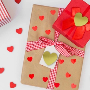 Heart stickers in gold and red applied on gift box packaging with red ribbons