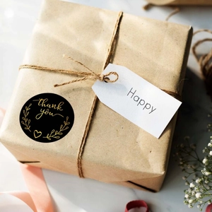 Close-up of black and gold thank you sticker on a kraft gift box for business packaging
