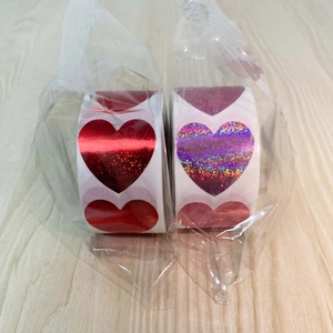 Close-up of glitter heart stickers in red and purple holographic finish on wooden table