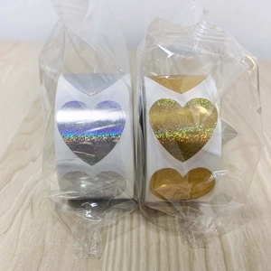 Macro view of gold and silver holographic heart stickers in plastic roll packaging