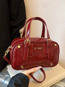 Elegant burgundy glossy leather boston handbag with golden hardware and shoulder strap