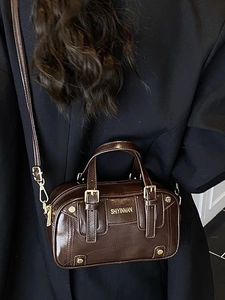 Deep brown glossy Boston handbag worn as a stylish crossbody bag on a black blazer