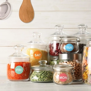 Detailed view of colorful weekday planner stickers used on glass kitchen storage jars