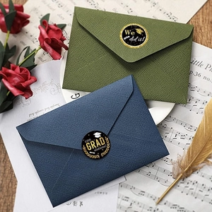 Detailed view of black and gold graduation stickers on colorful envelopes