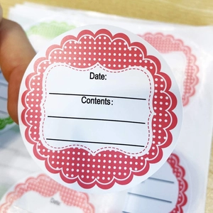 Close-up of round food storage labels with Date and Contents fields on wooden desk