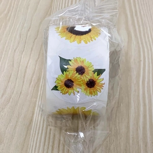 Detail of round sunflower thank you stickers roll in clear packaging on wood background