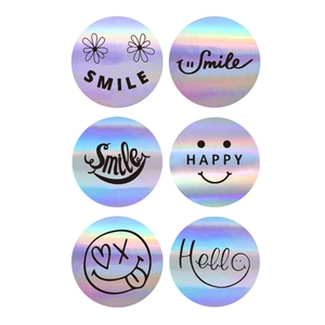 Dettaglio di adesivi laser olografici da 2,5 cm con motivi Smile e Hello su sfondo bianco