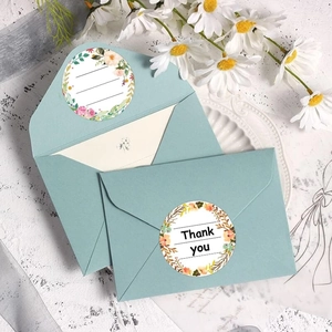 Macro shot of floral Thank You seal stickers on a mint envelope with daisy accents