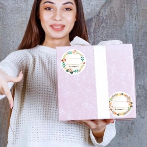 Détail d'étiquettes florales homemade sur une boîte cadeau avec un ruban blanc chic