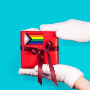 Detail of red gift box with satin bow and Progress Pride flag label on blue background
