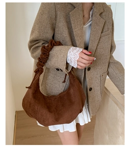 Detailansicht einer braunen Wildleder-Halbmondtasche mit Retro-Faltenriff am Model