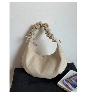 Detail der beigen Halbmondtasche mit Faltenhenkel und matter Wildlederoptik im Minimal-Stil