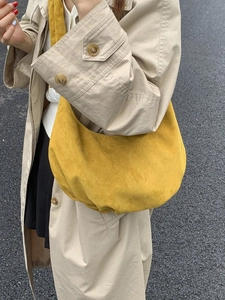 Senfgelbe Hobo-Schultertasche mit mattem Finish getragen von einem Model im beigen Mantel