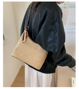 Detailed view of beige suede shoulder bag with vintage beaded tassel accessory