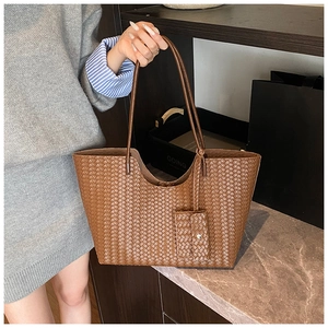 Detailed view of brown woven leather tote bag texture with matching mini flap pouch