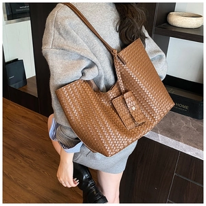 Brown woven tote bag shown on shoulder with matching mini pouch for daily commute