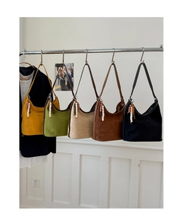 Detail of vintage suede bucket shoulder bags in five colors on a display rack.