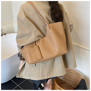 Close-up of brown woven leather tote bag with matching pouch shown on a model