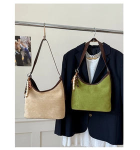 Retro suede shoulder bags in beige and green hanging on a rod with vintage accessories