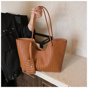 Detail of a brown woven tote bag with matching pouch on a minimalist background