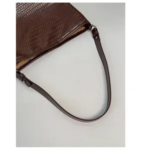 Detailed view of the dark brown woven texture and smooth leather strap of this bucket bag