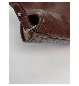 Detail of dark brown woven bucket bag showing silver D-ring and precise stitching