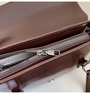Detailed interior of dark brown shiny leather bag showing zipper and quality stitching
