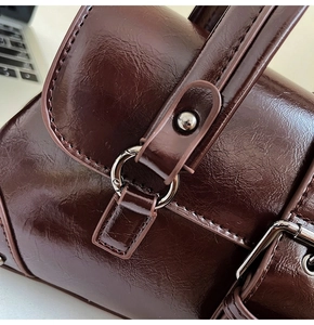 Macro detail of dark brown oil wax leather shoulder bag with polished metal buckle