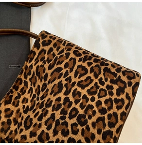 Gros plan sur la texture léopard et la poignée en cuir marron foncé du sac seau