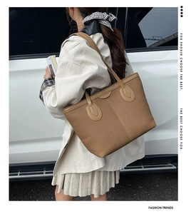 Detailed side view of a large brown canvas tote bag with leather trim and stitching