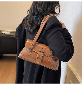 Detail of vintage brown leather underarm bag with silver rivets and buckle on model