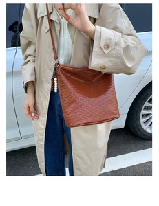 Detail of a brown woven leather bucket bag featuring a vintage wooden beaded tassel charm