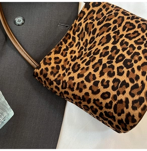 Macro shot of faux leopard fur texture and brown strap stitching on bucket bag