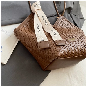 Detail of dark brown woven leather tote bag with branded ribbon and fashion tag
