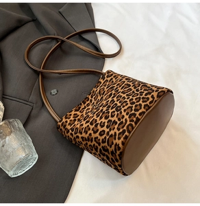 Détail de sac seau à motif léopard avec base en cuir marron sur fond de tissu